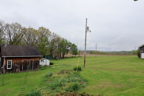 Paisaje rural con un granero de madera, un poste de electricidad y un campo cubierto de hierba.