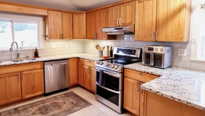 A kitchen with wooden cabinets, stainless steel appliances, a dishwasher, and a built-in oven. - The Homestead at Anderson Ridge |Pool & Trails (Schellsburg)