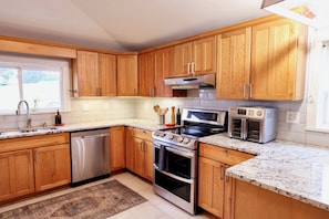 A modern kitchen with wooden cabinets, stainless steel appliances, a built-in oven, and a microwave.