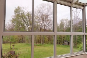 Una habitación con ventanas amplias que dan a un patio con césped y árboles.