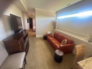 Ein Wohnzimmer mit Fernseher, Sofa und einem Fenster mit Jalousien.
