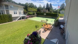 En bostadsträdgård med en tennisbana, utemöbler och en flagga.
