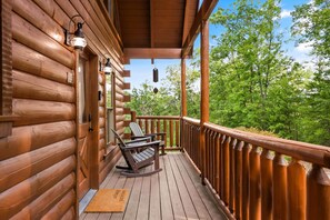 A wooden cabin with a deck, two Adirondack chairs, and a view of a forest. - Smoky Mountain Views near Pigeon Forge  Hot Tub, Game Room & 3 Decks (Sevierville)