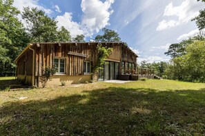 A rustic wooden cabin with a large glass door, surrounded by a grassy yard and trees. - La bergerie - ESCALANS (ESCALANS)