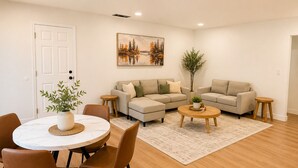 Ein Wohnzimmer mit einem runden Esstisch, zwei Sofas, einem Couchtisch und einer Zimmerpflanze.
