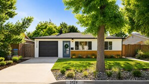 Einbungalow mit einer Garage, einem gepflegten Rasen und einem Baum im Vorgarten.