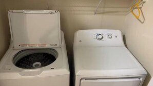 Ein Waschraum mit einer Frontlader-Waschmaschine und einem Trockner, einer Bedienkonsole und einem Stromkabel.