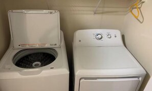 A laundry room with a front-loading washer and dryer, a control panel, and a power cord. - Lovely 2-bedroom house in vibrant Durham (Durham)