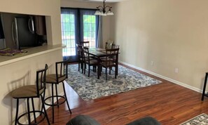 A dining area with a table and chairs, a bar area with stools, and a kitchen with a refrigerator. - Lovely 2-bedroom house in vibrant Durham (Durham)