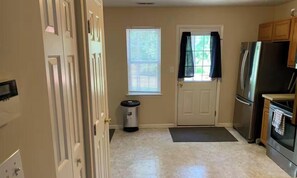A kitchen with a refrigerator, oven, and a window with blinds. - Lovely 2-bedroom house in vibrant Durham (Durham)