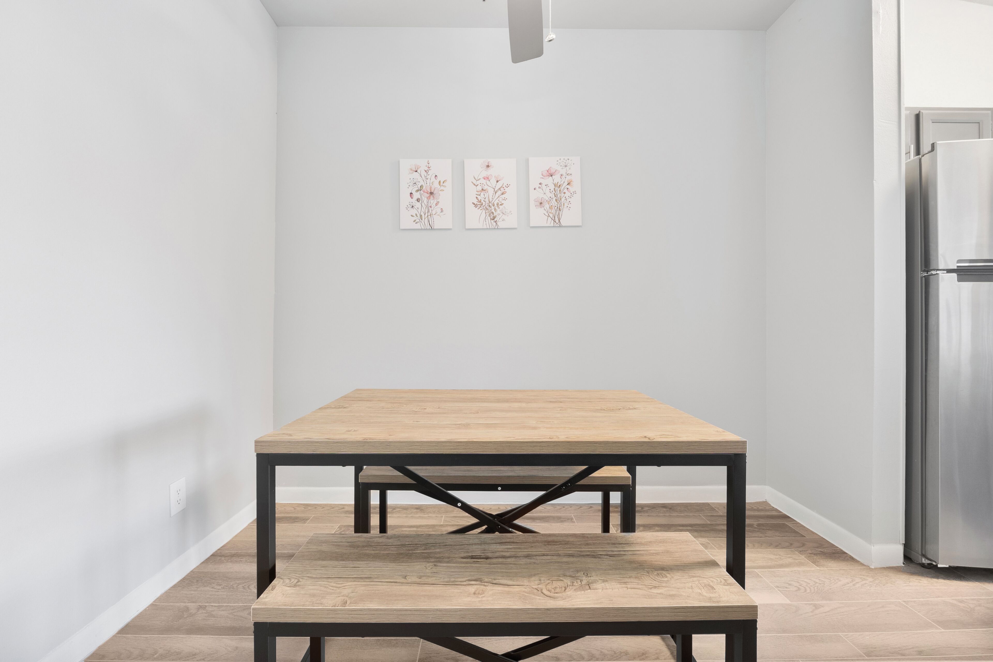A kitchen with a wooden table, white walls, and a stainless steel refrigerator.