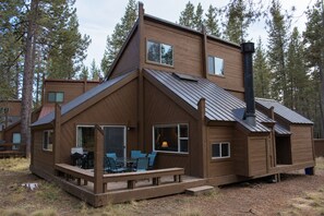 A two-story wooden cabin with a deck, large windows, and a chimney. - Walk to SHARC, Near Village, Hot Tub, Sleeps 13, Quiet Cul-De-Sac, Pet friendly (Sunriver)