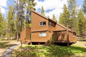Une cabane dotée d’un toit à forte pente, de nombreuses fenêtres et d’un escalier menant à l’entrée.