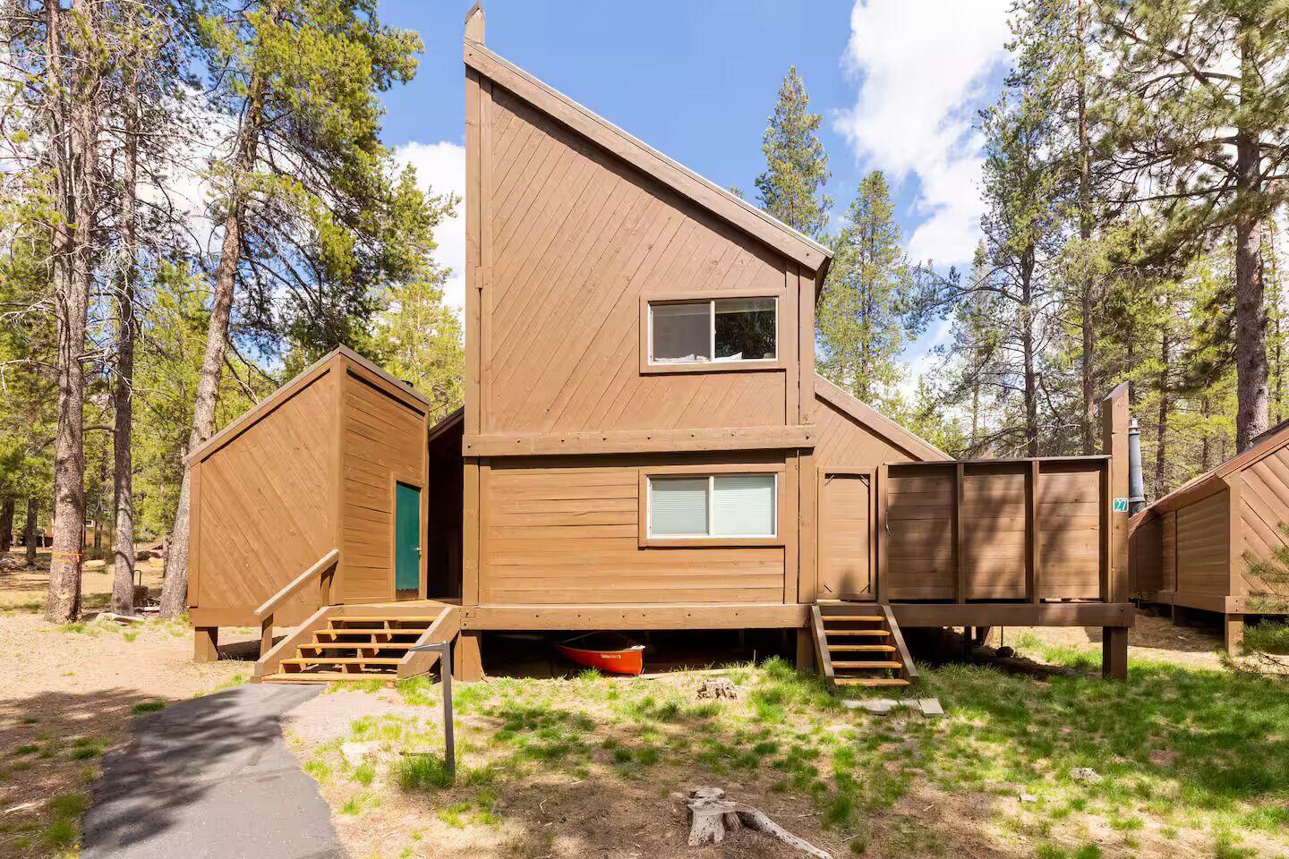 A wooden cabin with a steep roof, a front door, and a small porch area.