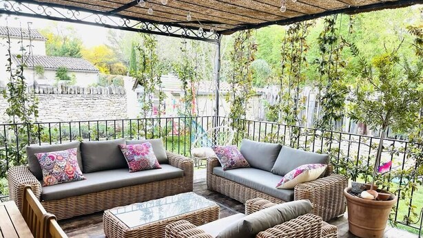 An outdoor patio with wicker furniture, a table, and a potted plant. - Stone farmhouse in the heart of the Luberon (Ménerbes)