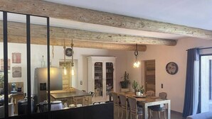 A dining area with a wooden ceiling, a white cabinet, and a dining table with chairs. - Stone farmhouse in the heart of the Luberon (Ménerbes)