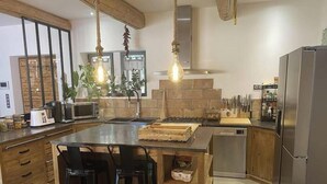 A modern kitchen with a central island, hanging light fixtures, and a built-in stove. - Stone farmhouse in the heart of the Luberon (Ménerbes)