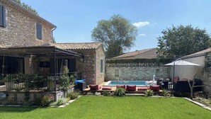 A stone house with a swimming pool, outdoor seating, and a well-maintained lawn. - Stone farmhouse in the heart of the Luberon (Ménerbes)