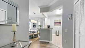 Une cuisine moderne dotée d’un îlot central, d’un coin repas avec des chaises et d’un couloir menant à une chambre.