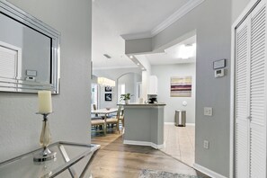 Une cuisine moderne dotée d’un îlot central, d’un coin repas avec des chaises et d’un couloir menant à une porte.