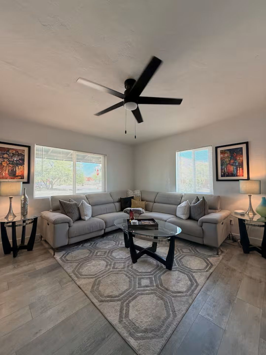 A living room with two sofas, a coffee table, a ceiling fan, and artwork on the walls.