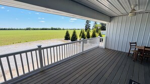 Une terrasse extérieure couverte, dotée d’une rambarde, d’une table et de chaises.