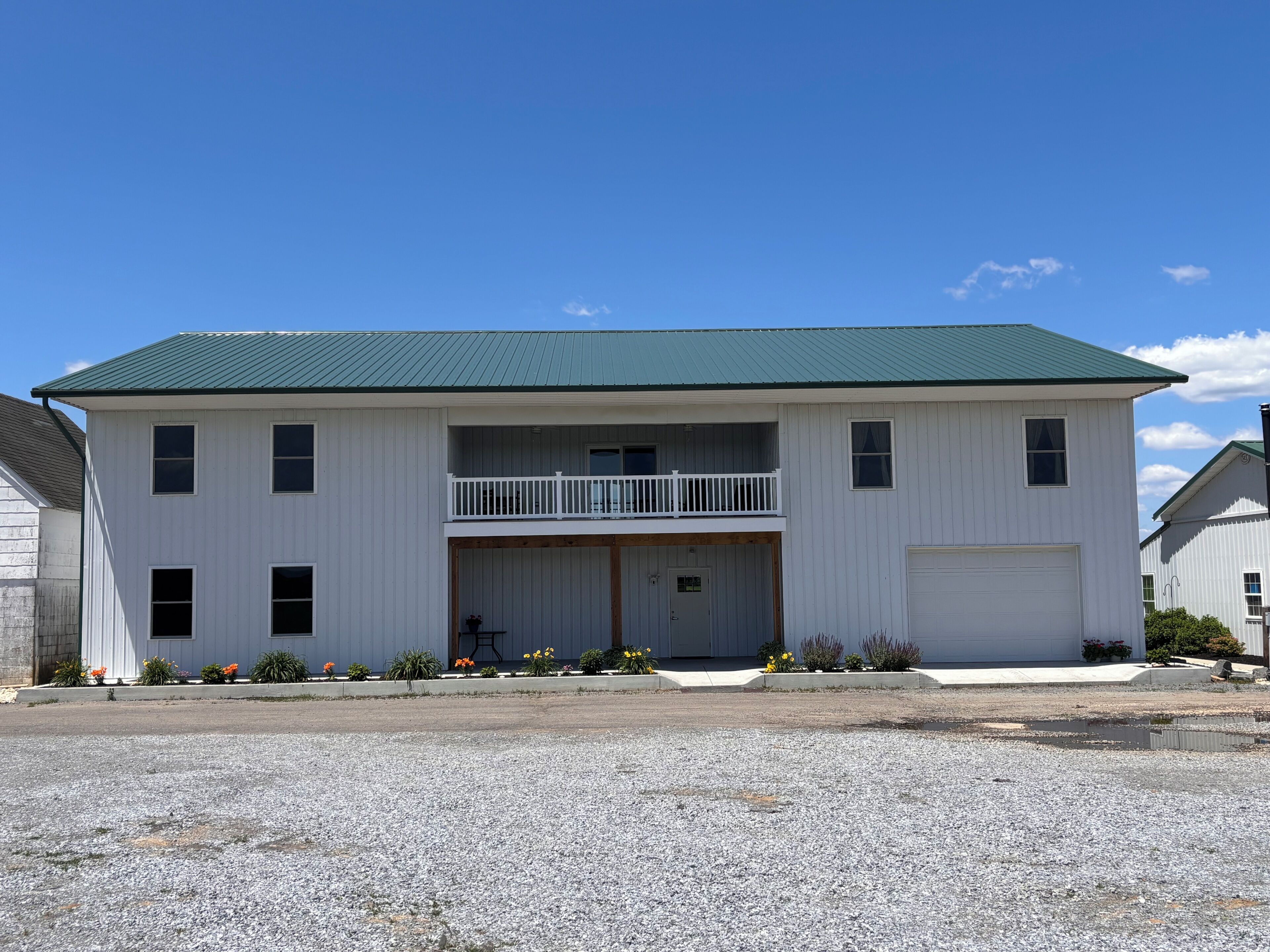 A two-story building with a green roof, a front porch, and a garage.
