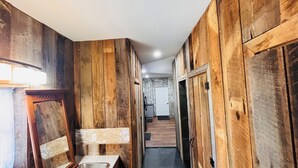 Un couloir aux murs en bois et muni d’un lavabo.