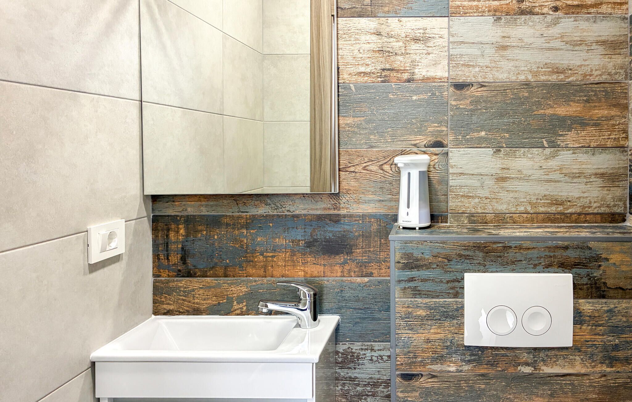 Une salle de bain avec un lavabo blanc, un miroir et un mur en bois intégrant un radiateur.