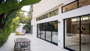 Uma casa moderna com um pátio, janelas amplas e um espaço de jantar.