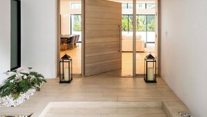 Interior moderno com uma porta de madeira deslizante que dá para uma sala de jantar, duas lanternas pretas e uma planta branca.