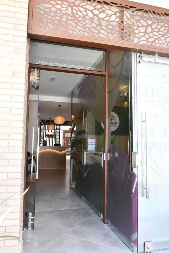 A reception area with a glass door, a reception desk, and a decorative wall with a leaf pattern.