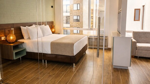 Moderni hotellihuone, jossa on suuri sänky, yöpöydät, työpöytä ja näkymä kaupungin ylle.