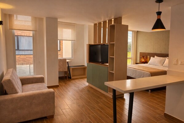 Una habitación moderna con sofá, televisión, mesa de comedor y cama.