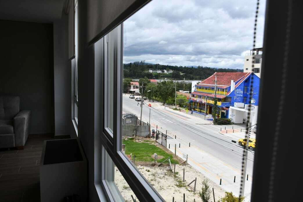 Una habitación con un ventanal grande que da a una calle con edificios y una carretera.