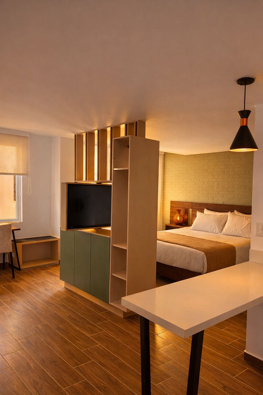 Una habitación de hotel compacta con cama, escritorio, televisión y kitchenette.