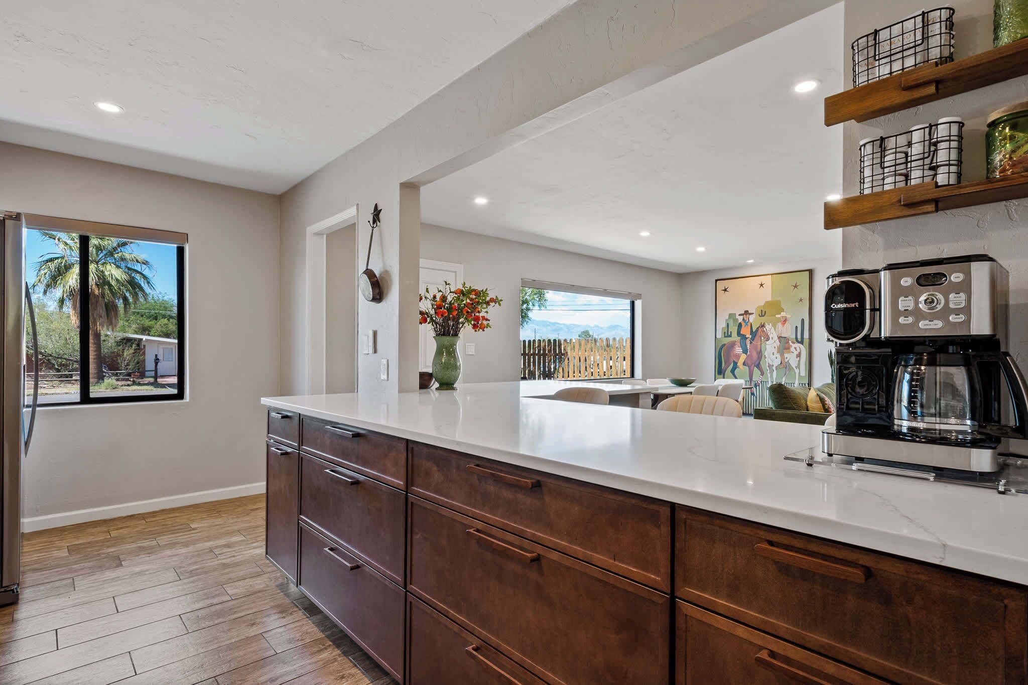 A modern kitchen with a large island, wooden cabinets, and a coffee machine.
