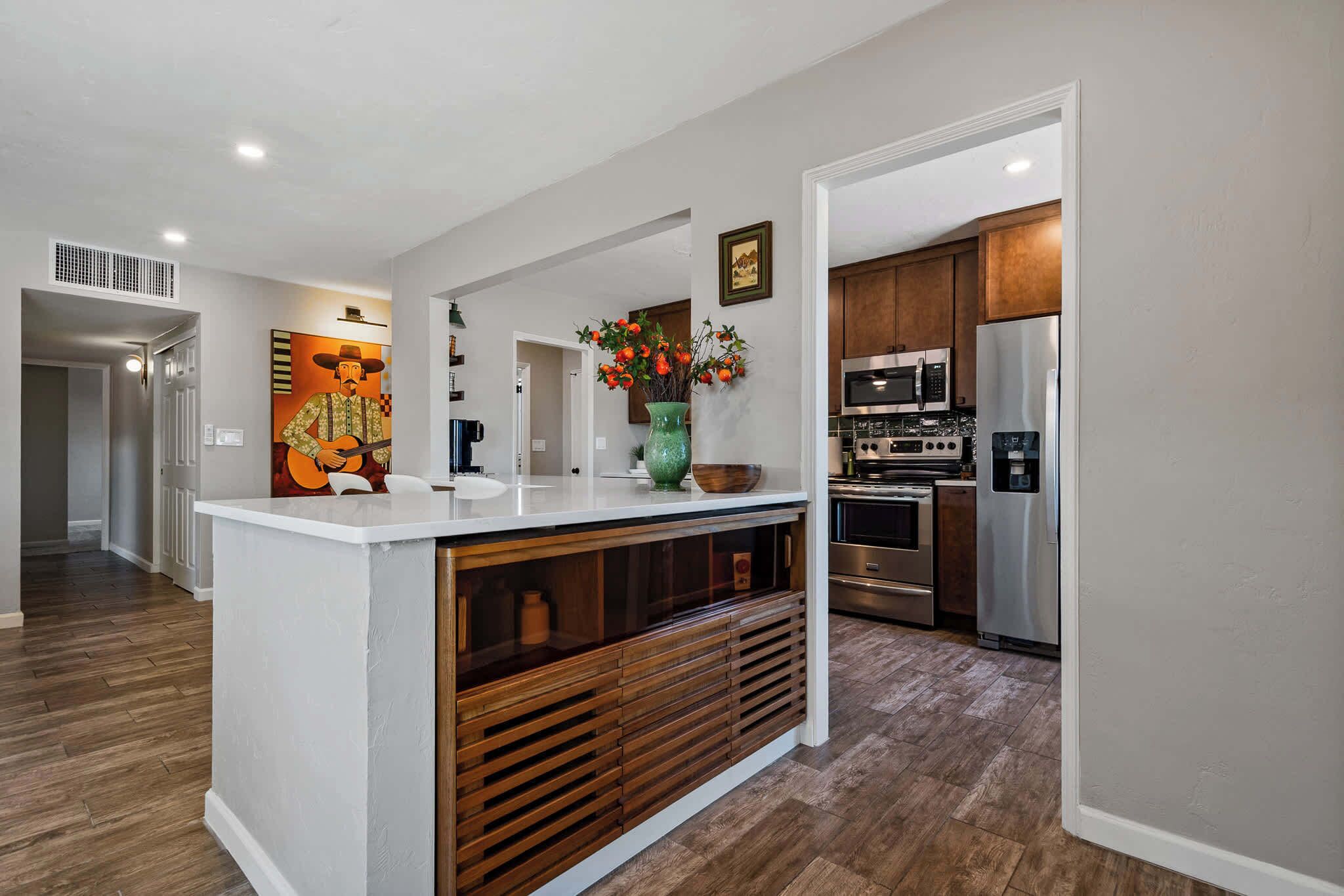 A modern kitchen with a central island, stainless steel appliances, and a decorative wall piece.