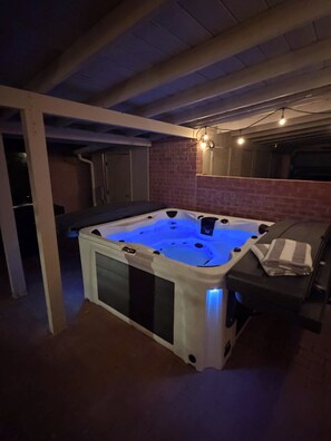 A hot tub in a room with brick walls, a ceiling with exposed beams, and a small window. - 2nd Street Tucson - Desert Modern Boutique Rental (Tucson)