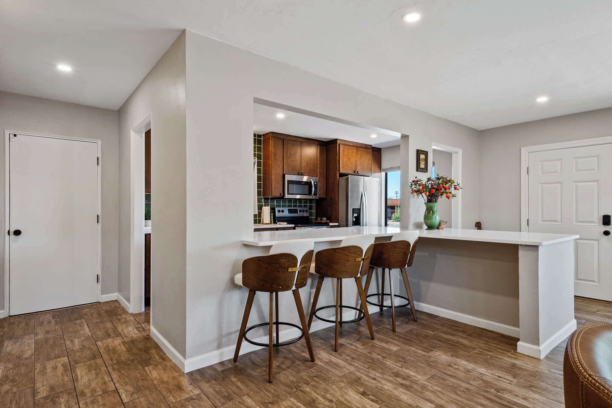 A modern kitchen with a central island, bar stools, and stainless steel appliances.