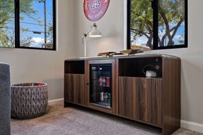 A room with a wooden cabinet with glass doors, a small rug, a woven basket, and a wall clock. - 2nd Street Tucson - Desert Modern Boutique Rental (Tucson)