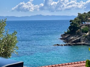 Küstliche Ansicht mit blauem Himmel, felsigem Ufer und einem Gebäude mit rotem Dach.