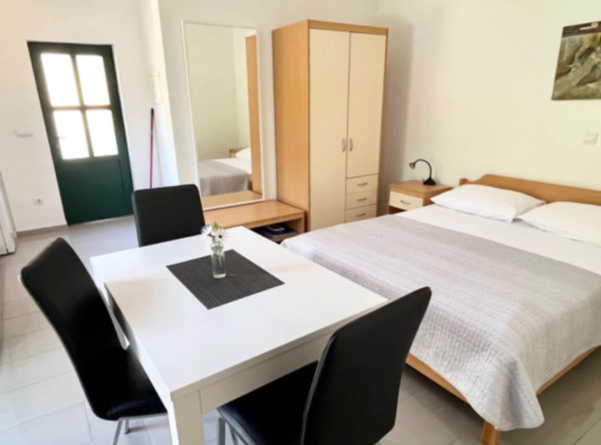 Ein Hotelzimmer mit einem Bett, einem Schreibtisch, einem Stuhl, einem Kleiderschrank und einem Spiegel.