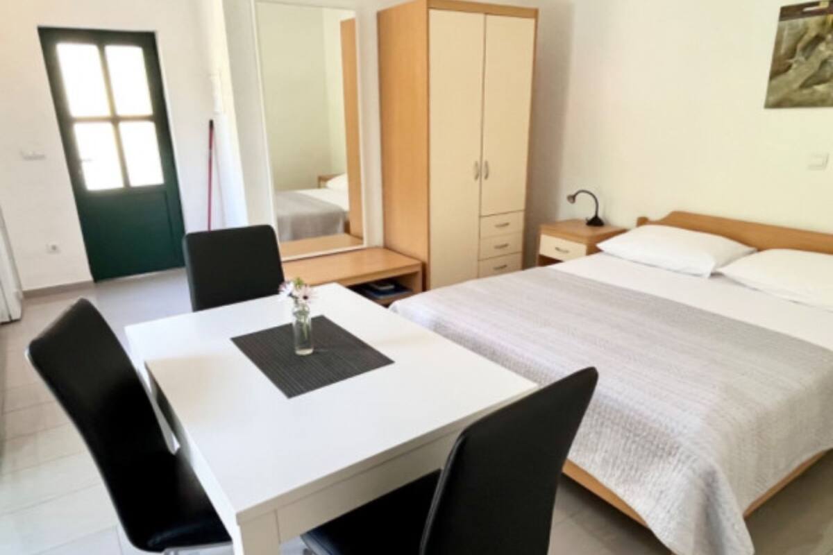 A hotel room with a bed, a desk, a chair, a wardrobe, and a mirror.