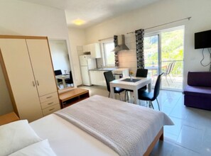 A bedroom with a bed, a desk, and a kitchenette. - Paradise Apartments (Jelsa)