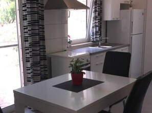 Eine moderne Küche mit weißen Schränken, einer Edelstahlspüle und einem Fenster mit Vorhängen.