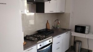 A kitchen with a stove, oven, sink, and microwave. - Comfort Apartments Orma (Povljana)