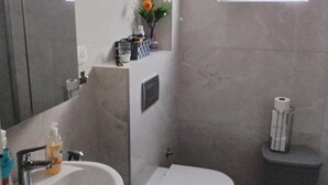 A bathroom with a sink, toilet, and a small window with flowers. - Comfort Apartments Orma (Povljana)