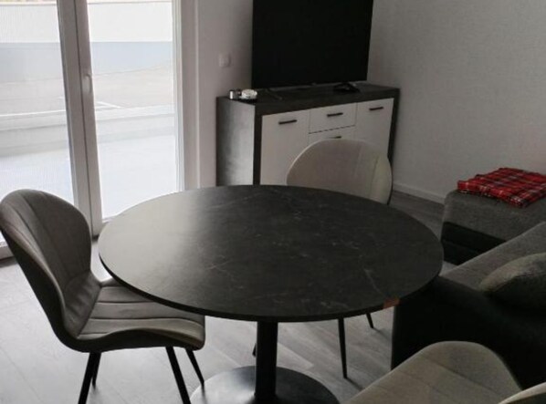 A modern room with a round table, two chairs, a sofa, a cabinet, and a TV. - Comfort Apartments Orma (Povljana)