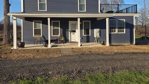 A two-story house with a covered porch, a front door, and a visible mailbox. - Spacious 2-bedroom house in Stone Ridge with outdoor patio with beautiful view. (Stone Ridge)